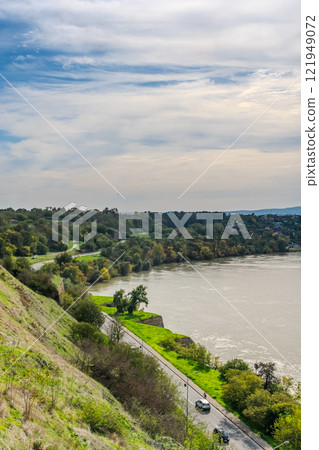 The fortress perched on Petrovaradin Hill watches over the city, while the charming streets and modern buildings of Novi Sad are spread out, creating a perfect blend of history and contemporary life 121949072