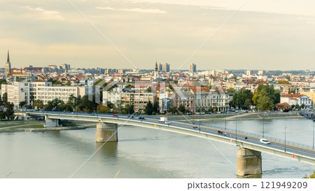 A panoramic city view of Novi Sad with its iconic bridge over the Danube River is a breathtaking sight. From this vantage point, the city sprawls beneath the sky, with the elegant Varadin Bridge A panoramic city view of Novi Sad with its iconic bridge over the Danube River is a breathtaking sight. From this vantage point, the city sprawls beneath the sky, with the elegant Varadin Bridge 121949209