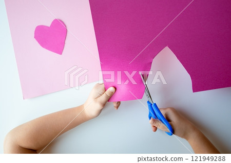 Child cutting pink heart from paper for creative Valentines day craft Child cutting pink heart from paper for creative Valentines day craft 121949288