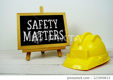 Safety Matters text on blackboard with safety helmet on wooden background 121949613