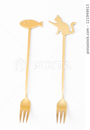 Two golden forks with decorative handles featuring cat and fish shapes, isolated on a white background Two golden forks with decorative handles featuring cat and fish shapes, isolated on a white background 121949913