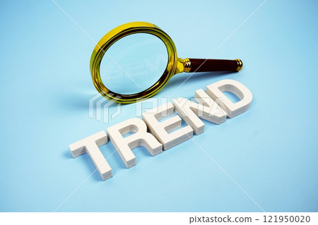 Trend word with magnifying glass top view on blue background 121950020