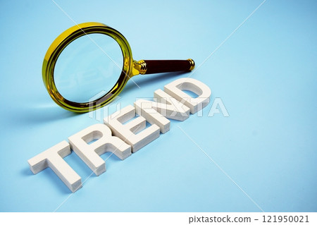 Trend word with magnifying glass top view on blue background Trend word with magnifying glass top view on blue background 121950021