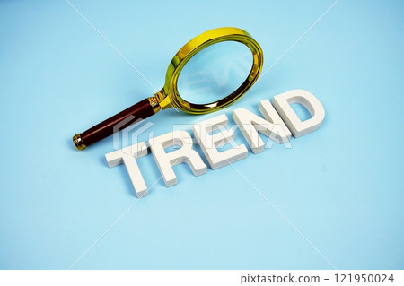 Trend word with magnifying glass top view on blue background Trend word with magnifying glass top view on blue background 121950024