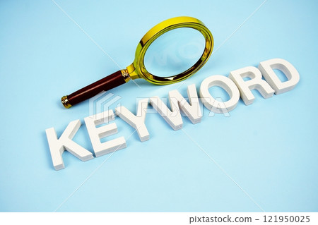 Keyword word with magnifying glass top view on blue background 121950025
