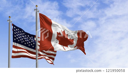 Canada and american national flags waving in the wind on a clear day 121950058