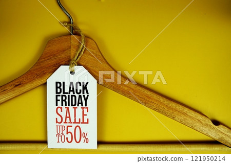 Black Friday Sale up to 50% on price tag with wooden clothes hanger top view on yellow background Black Friday Sale up to 50% on price tag with wooden clothes hanger top view on yellow background 121950214