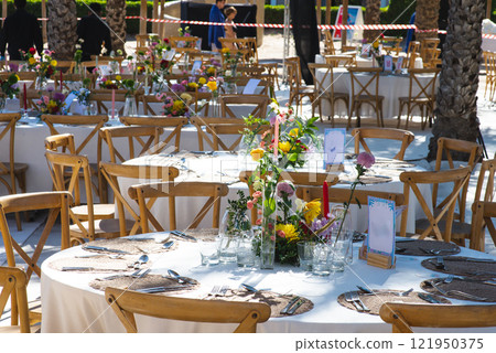 A chilled champagne bottle in ice, elegantly wrapped in a white napkin, stands ready at a luxurious outdoor event by the sea. The background shows gourmet appetizers, enhancing the celebration vibe A chilled champagne bottle in ice, elegantly wrapped in a white napkin, stands ready at a luxurious outdoor event by the sea. The background shows gourmet appetizers, enhancing the celebration vibe 121950375