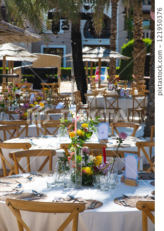 A chilled champagne bottle in ice, elegantly wrapped in a white napkin, stands ready at a luxurious outdoor event by the sea. The background shows gourmet appetizers, enhancing the celebration vibe A chilled champagne bottle in ice, elegantly wrapped in a white napkin, stands ready at a luxurious outdoor event by the sea. The background shows gourmet appetizers, enhancing the celebration vibe 121950376