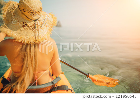 Woman in kayak back view. Happy woman with long hair in a swimsuit and hat floating in kayak on the sea. Summer holiday vacation. Summer holidays vacation at sea. 121950543