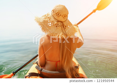 Woman in kayak back view. Happy woman with long hair in a swimsuit and hat floating in kayak on the sea. Summer holiday vacation. Summer holidays vacation at sea. Woman in kayak back view. Happy woman with long hair in a swimsuit and hat floating in kayak on the sea. Summer holiday vacation. Summer holidays vacation at sea. 121950544