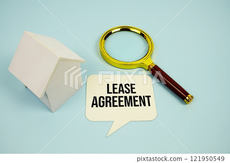 Lease Agreement text message on sticky note with magnifying glass and house model on blue background 121950549
