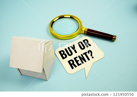 Buy Or Rent? text message on sticky note with magnifying glass and house model on blue background 121950550