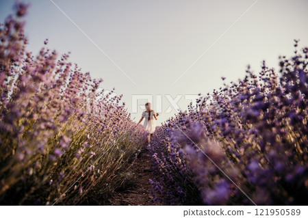 Lavender field girl. Back view happy girl in white dress with a scythe runs through a lilac field of lavender. Aromatherapy travel Lavender field girl. Back view happy girl in white dress with a scythe runs through a lilac field of lavender. Aromatherapy travel 121950589