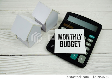 Monthly Budget text message on sticky note with home model and calculator on wooden Monthly Budget text message on sticky note with home model and calculator on wooden 121950789