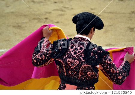 Traditional spanish bullfighter in ornate costume with cape in arena. Tauromaquia. Spanish traditions Traditional spanish bullfighter in ornate costume with cape in arena. Tauromaquia. Spanish traditions 121950840