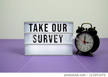 Take Our Survey text on light box with alarm clock on purple background Take Our Survey text on light box with alarm clock on purple background 121951078