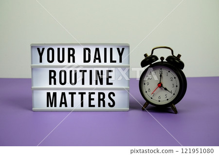 Your Daily Routine Matters text on light box with alarm clock on purple background 121951080