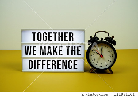 Together We Make The Difference text on light box with alarm clock on yellow background Together We Make The Difference text on light box with alarm clock on yellow background 121951101