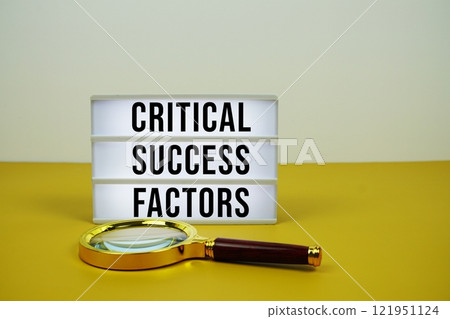 Critical Success Factors text on light box with magnifying glass on yellow background 121951124