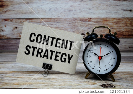 Content strategy text on paper card with alarm clock on wooden background 121951584