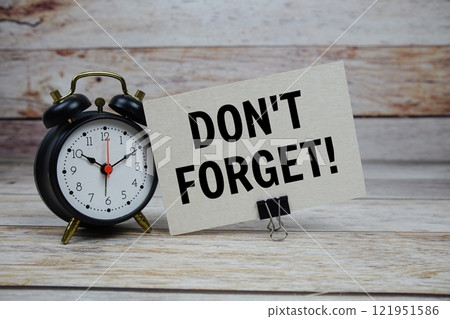 Don't Forget text on paper card with alarm clock on wooden background Don't Forget text on paper card with alarm clock on wooden background 121951586