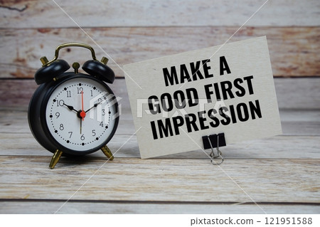Make a good first impression text on paper card with alarm clock on wooden background Make a good first impression text on paper card with alarm clock on wooden background 121951588