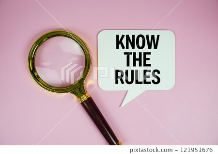 Know the Rules text on speech bluble with magnifying glass top view on pink background 121951676