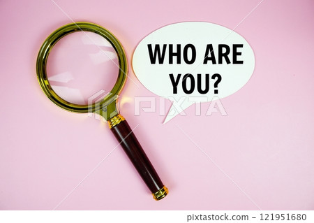 Who are you? text on speech bluble with magnifying glass top view on pink background 121951680