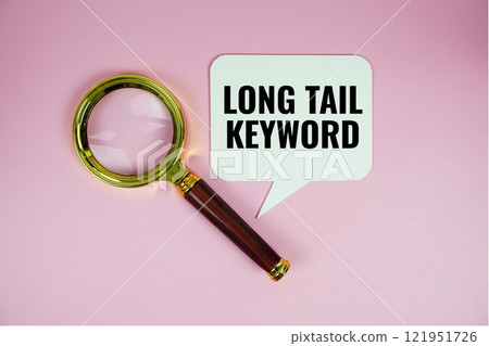 Long tail keyword text on speech bluble with magnifying glass top view on pink background 121951726