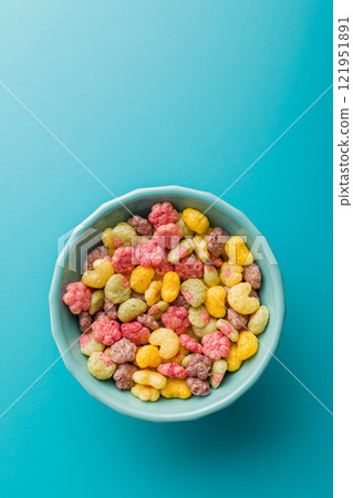 Colorful breakfast cereals in the shape of various fruit in bowl on blue background. Top view. 121951891
