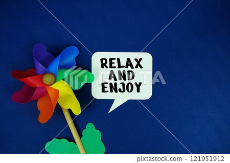 Relax and Enjoy text motivational and inspiration quote with colorful pinwheel top view on blue background Relax and Enjoy text motivational and inspiration quote with colorful pinwheel top view on blue background 121951912