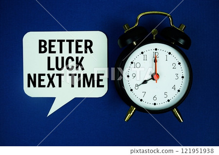 Better Luck Next Time text on speech bubble with alarm clock top view on blue background Better Luck Next Time text on speech bubble with alarm clock top view on blue background 121951938