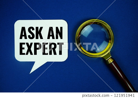 Ask an Expret text on speech bubble with magnifying glass top view on blue background 121951941