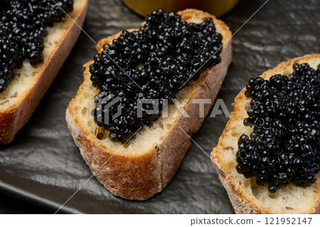 Sandwich with baguette and black caviar on a black board 121952147