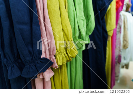 Brightly colored dresses hanging in a boutique showcasing vibrant summer styles 121952205