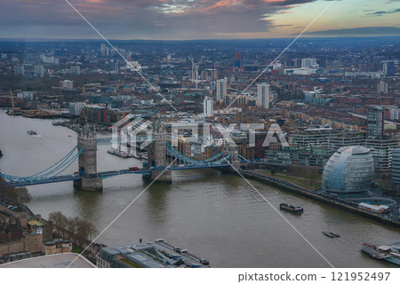The image captures Tower Bridge over the River Thames with City Hall nearby. Boats navigate the river, surrounded by historic and modern architecture. 121952497