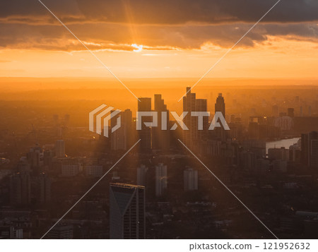 The London skyline is silhouetted against a vibrant sunset, with the River Thames winding through the city, creating a dramatic scene during Christmas. 121952632