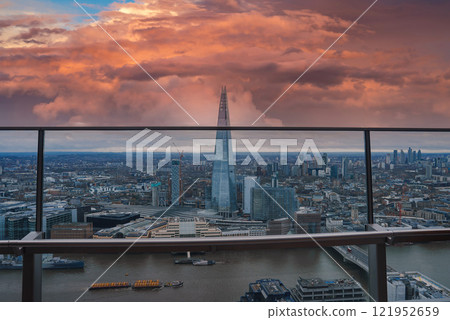 Aerial view of London during Christmas with The Shard in the center. The River Thames flows below, set against a sky of orange and pink hues. 121952659