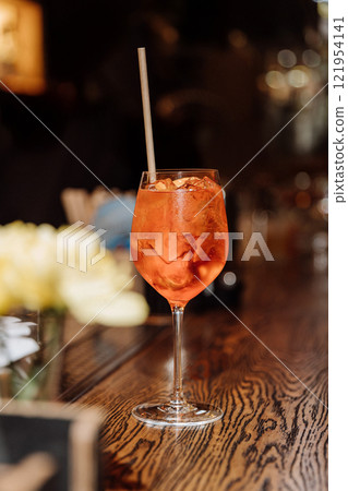 Single Aperol spritz on a rustic bar counter, exuding elegance and refreshing cocktail vibes Single Aperol spritz on a rustic bar counter, exuding elegance and refreshing cocktail vibes 121954141