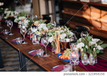 Elegant outdoor table setup with fresh fruit, flowers, and glassware for a festive gathering 121954150