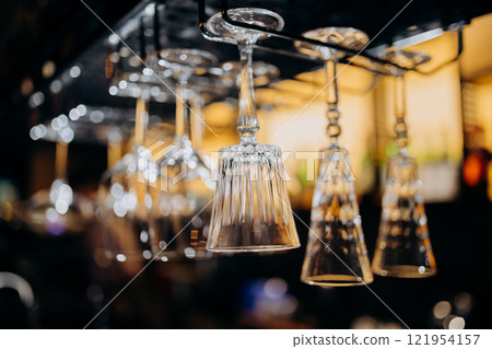 Elegant hanging glassware in a modern bar setting, perfect for upscale nightlife and fine dining Elegant hanging glassware in a modern bar setting, perfect for upscale nightlife and fine dining 121954157