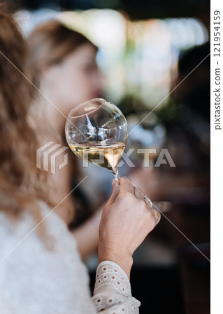 Close-up of a hand holding a wine glass at a sophisticated gathering, celebrating special moments 121954159