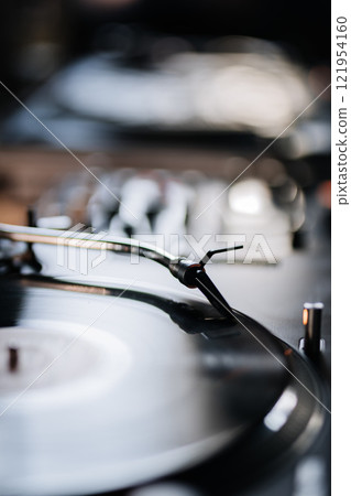Close-up of a turntable needle on a spinning vinyl record, embodying retro music and vintage vibes 121954160