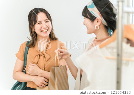 一名女性顧客在服飾店/雜貨店收銀台領取商品 一名女性顧客在服飾店/雜貨店收銀台領取商品 121954353
