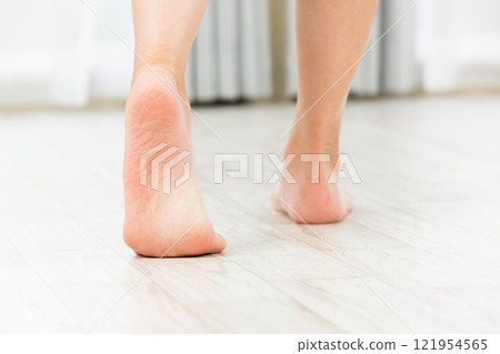 一位年輕的亞洲女子赤腳走在木地板上。 一位年輕的亞洲女子赤腳走在木地板上。 121954565