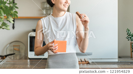 Young Asian woman in yoga wear eating a protein/nutrition bar 121954829
