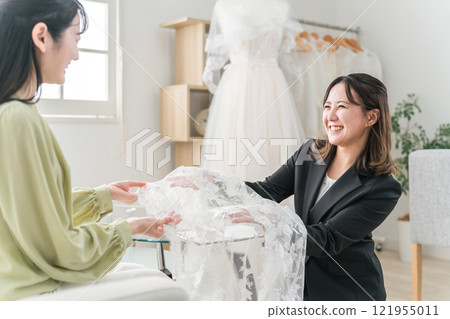 一位女士前來試穿婚紗，並與婚禮策劃師/禮服協調員會面。 121955011