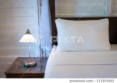 Pillows on bed and bedside table and a lamp on it. Pillows on bed and bedside table and a lamp on it. 121955692