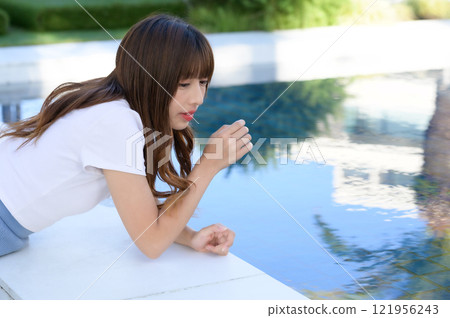 Woman standing by the pool 121956243